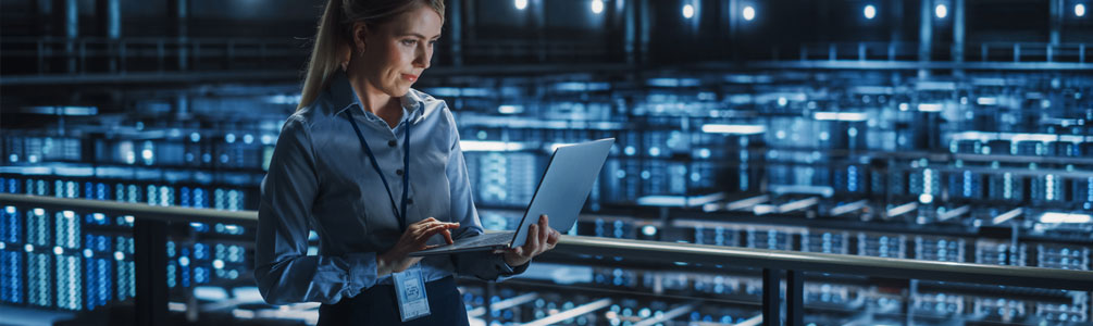 Professional standing in server farm using laptop