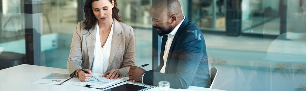 Two professionals at a table reviewing documents